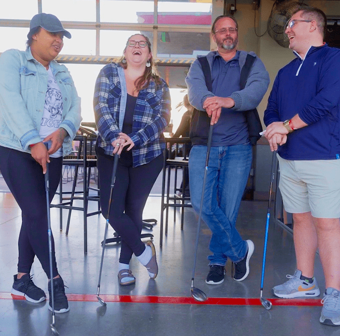 PSIvet Business Symposium 4 attendees standing next to one another holding golf clubs while laughing and seeming to have a great time