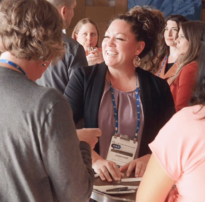 PSIvet Business Symposium attendee looks off to the side over her right shoulder while smiling and speaking to other attendees and networking